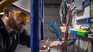 electrician working on switchboard and cables