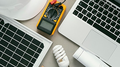 top view of laptop, solar panel and light bulb